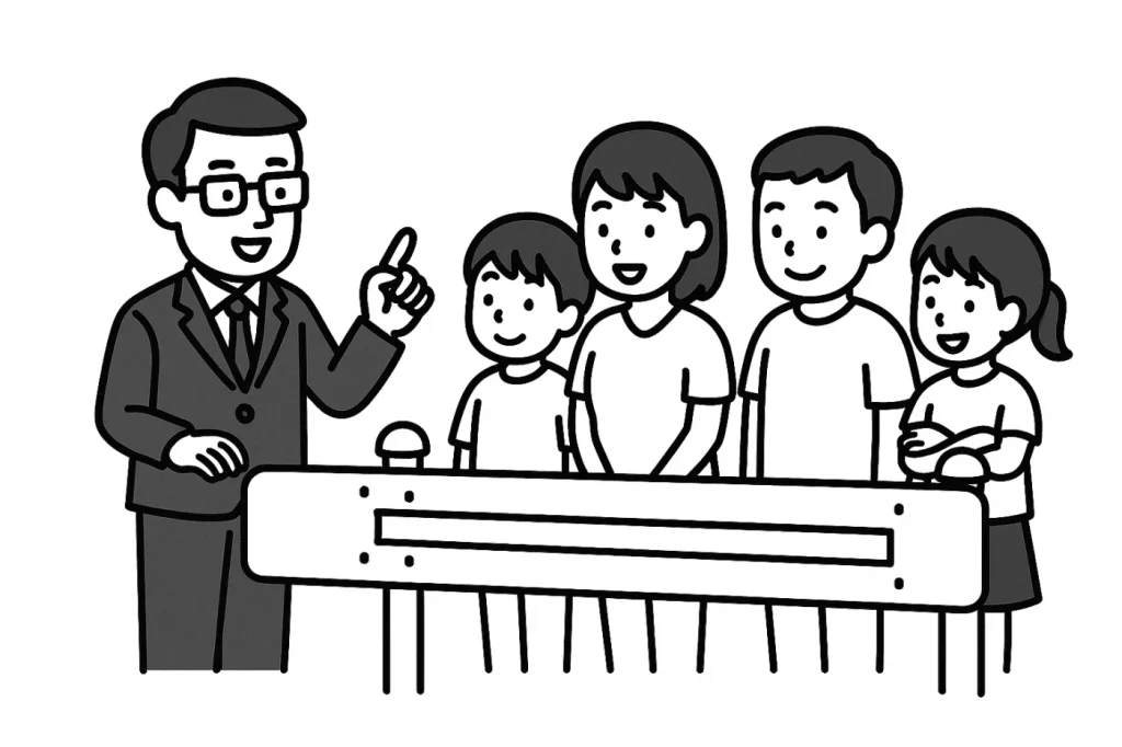 眼鏡をかけたスーツ姿の男性が人差し指を立てて説明し、4人家族(父母と子ども2人)が笑顔でガードレールの前に立っているモノクロイラスト